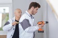 Apprentice supervised by trainer while drilling wall Royalty Free Stock Photo