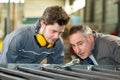 Apprentice and teacher working with metal bars in factory