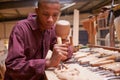 Apprentice Using Chisel To Carve Wood In Workshop