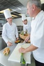 Apprentices cooks watching chef garnishing dish Royalty Free Stock Photo