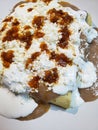 approach to a plate of enfrijoladas, traditional mexican food, tortillas bathed in bean sauce with cream, cheese and hot sauce