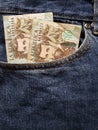 approach to front pocket of jeans in blue with Colombian banknotes