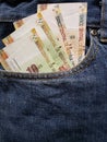 approach to front pocket of jeans in blue with Peruvian banknotes
