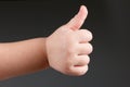 Approval thumbs up like sign, child hand gesture over dark background