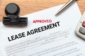 Approved lease agreement document with rubber stamp and calculator on wooden desk. Royalty Free Stock Photo