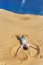 Appy guy laying on sand and making sand angel. Royalty Free Stock Photo