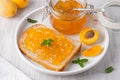 Apricot jam on bread in a white plate and a jar of apricot jam Royalty Free Stock Photo