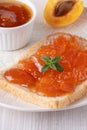 Apricot jam on bread in a white plate and a jar of apricot jam Royalty Free Stock Photo