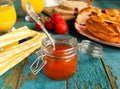 Apricot jam in a jar with a silver spoon on the table at breakfast. Two glasses with orange juice, cherry pie, ripe strawberries, Royalty Free Stock Photo