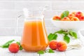 Apricot juice and fresh fruits with leaves on white wooden table Royalty Free Stock Photo