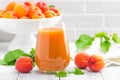 Apricot juice and fresh fruits with leaves on white wooden table Royalty Free Stock Photo