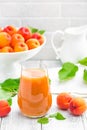 Apricot juice and fresh fruits with leaves on white wooden table Royalty Free Stock Photo