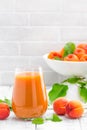 Apricot juice and fresh fruits with leaves on white wooden table Royalty Free Stock Photo