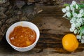 Apricot and peach jam in a small deep dish, sweet orange jam for dessert. Next to a whole fruit, apricots are marinated in syrup.