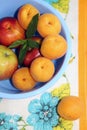 Apricots and apples in blue plastic bowl on napkin.