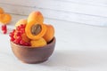 apricots and red currants in a wooden bowl on a wooden background, copy space Royalty Free Stock Photo