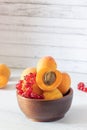 apricots and red currants in a wooden bowl on a white background, copy space Royalty Free Stock Photo