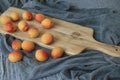 Apricots standing on wooden piece. Gray cover in the background