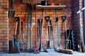 Light falls on an armoury of well used garden tools.