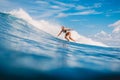 April 04, 2021. Bali, Indonesia. Sporty young woman in tropical ocean during surfing. Surfer girl on surfboard and perfect wave