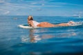 April 04, 2021. Bali, Indonesia. Young surfgirl in tropical ocean paddle on surfboard