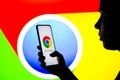 April 27, 2022, Brazil. In this photo illustration, a silhouetted woman holds a smartphone with the Google Chrome logo displayed