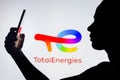 April 4, 2022, Brazil. In this photo illustration, a woman`s silhouette holds a smartphone with the TotalEnergies SE logo in the