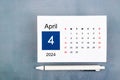 April Calendar 2024 page with pen on blue wooden