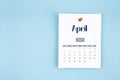 April 2026 calendar page with push pin on blue background Royalty Free Stock Photo