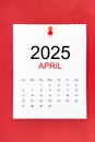 April 2025 calendar page with push pin on red background Royalty Free Stock Photo