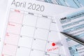 April 2020 calendar with the 15th pinned with tax day text, and 1040 tax forms on the sides