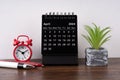 April 2024 desk calendar, alarm clock and potted plant
