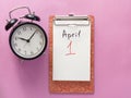 1 april fool's day, notebook, clock, pen. Flat lay on pink background Royalty Free Stock Photo