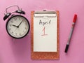 1 april fool's day, notebook, clock, pen. Flat lay on pink background Royalty Free Stock Photo