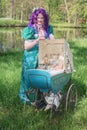 Dressed woman with a purple wig and antique pram filled with glass jars with candy Royalty Free Stock Photo