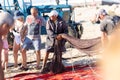 24 April 2023 Lisbon, Portugal: male fishermen holding freshly caught fish in the net standing on the shore