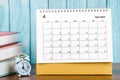 The April 2023 Monthly desk calendar for the organizer to plan 2023 year with alarm clock and books on wooden table