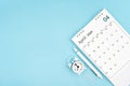 April 2024, Monthly desk calendar for 2024 year and alarm clock with paper clips on blue color background Royalty Free Stock Photo