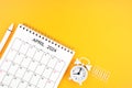 April 2024, Monthly desk calendar for 2024 year and alarm clock with paper clips on yellow color background Royalty Free Stock Photo