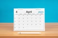 The April monthly desk calendar for 2024 year and pen on wooden table with blue color background