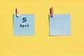 April 5st. Day of 5 month, calendar date. Two blue sheets for writing on a yellow background. Top view, copy space. Spring month,
