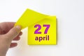 April 27th. Day 27 of month, Calendar date. Hand rips off the yellow sheet of the calendar. Spring month, day of the year concept