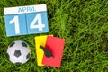 April 14th. Day 14 of month, calendar on football green grass background with soccer outfit. Spring time