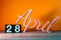 April 28th. Day 28 of month, daily wooden calendar on table with orange background. Spring time concept