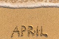 April - word drawn on the sand beach with the soft wave. Royalty Free Stock Photo