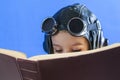 April 23, World Book Day, Concept - reading and enlightenment - the path to knowledge, a boy in a pilot helmet reads a book Royalty Free Stock Photo