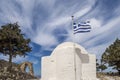 The apse of a typical Greek church with the flag in the wind among the ruins of the medieval castle Monolithos, Rhodes, Greece