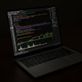 aptop displaying programming code and a stock chart on the screen. The dark- Royalty Free Stock Photo