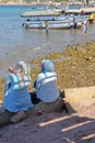 Women sitting in front of the beach with Glass boats in the background