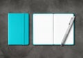 Aqua blue closed and open lined notebooks with a pen on dark concrete background